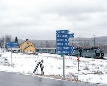 Information sign on snow covered road against sky
