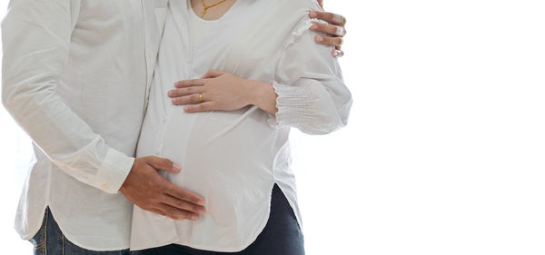 Midsection of woman standing against white background