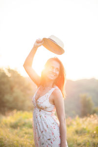 Smiling woman looking away against sky during sunset