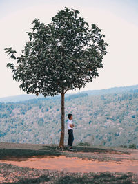 Man standing by tree against sky