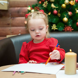 A little girl draws on the background christmas tree. the concept of waiting for the holiday.