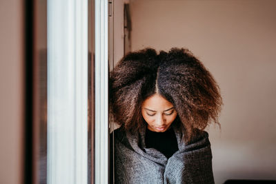 Woman with afro hair looking down by window