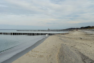 Wooden posts on beach by sea against sky