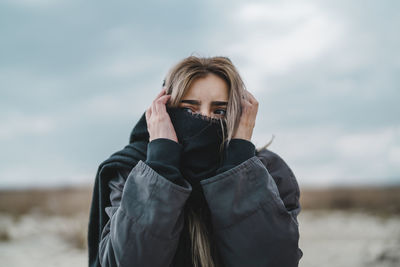 Portrait of young woman standing against the sky