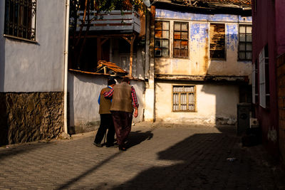 Full length rear view of men walking on street amidst buildings