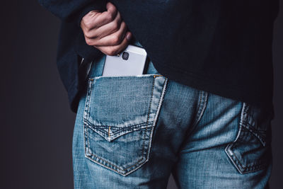 Midsection of man keeping mobile phone in pocket