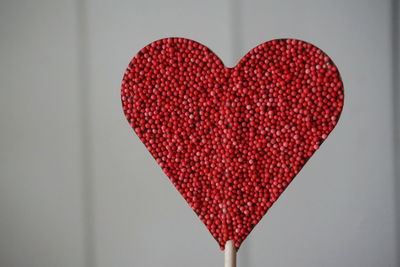 Close-up of red heart shape candy against wall