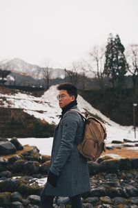 Side view of young man standing on rock