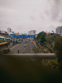 Road by buildings in city against sky