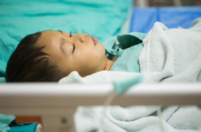 High angle view of cute boy lying on bed in hospital