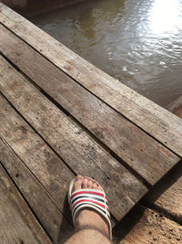 Low section of person standing on pier over lake