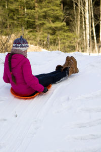 Rear view of woman tobogganing on snow