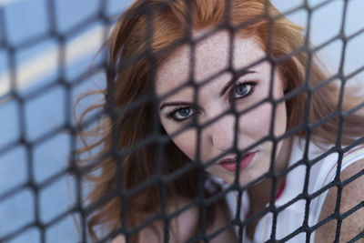 Close-up portrait of woman looking through fence