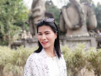 Portrait of smiling woman standing against statues