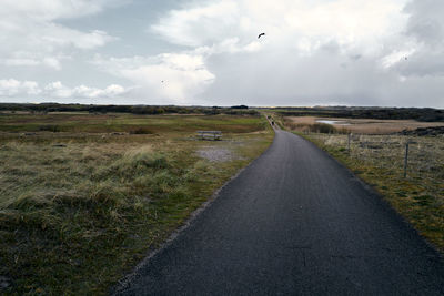 Road amidst field against sky