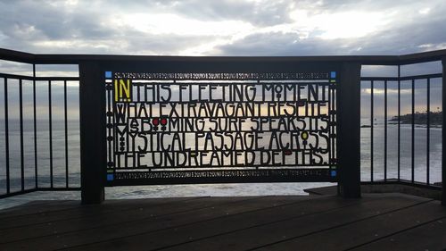 Sign board against cloudy sky