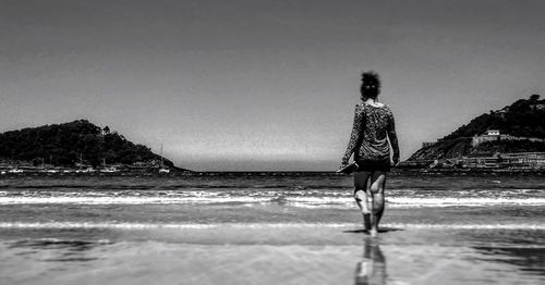 Rear view of woman walking on beach