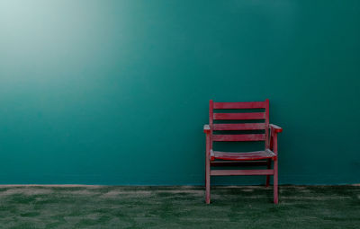 Red chair against green wall on tennis court 