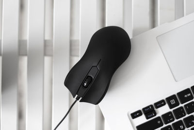 Black mouse on top of a white laptop.