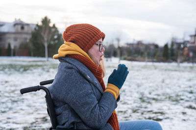 Side view of woman sitting on bench