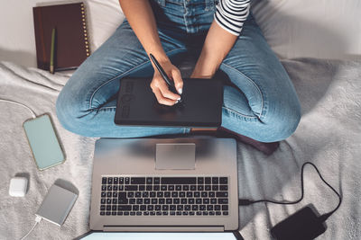 Midsection of woman using mobile phone while sitting on table