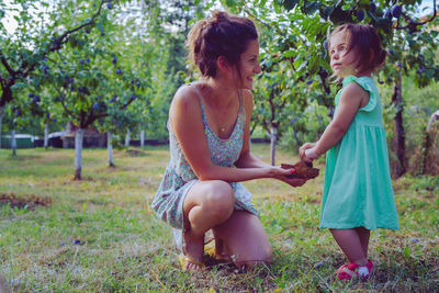 Woman with daughter picking grapes in vineyard