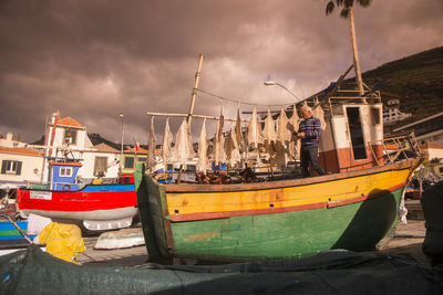 Boats moored at harbor against sky