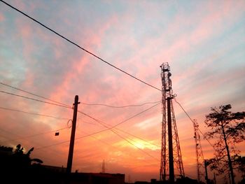 Low angle view of electricity pylon against cloudy sky