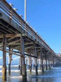 View of pier on beach against clear blue sky