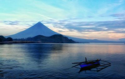 Boat on lake with mountain in background during sunrise