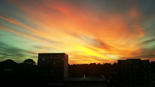 Silhouette of built structure against cloudy sky at sunset