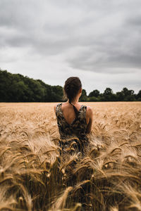 Young woman with dark braided hair standing in the middle of a wheat field