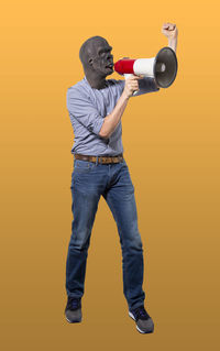 Full length of young man looking away against orange background