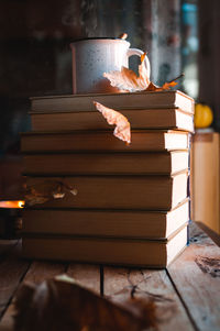 Stacked books and hot tea against rainy window