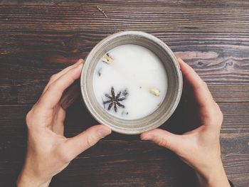 High angle view of woman holding coffee cup on table