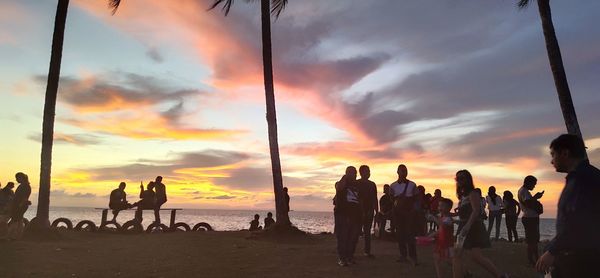 People on beach against sky during sunset