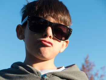 Low angle view portrait of boy wearing sunglasses against sky