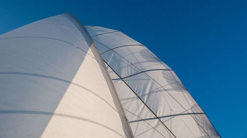 Low angle view of boat canvas against clear blue sky