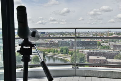 Bird perching on railing against sky seen through window