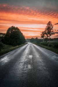 Road amidst field against sky during sunset