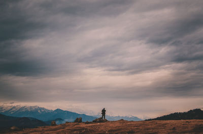 Man standing on mountain against sky during sunset