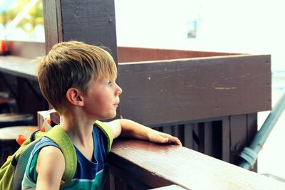 Boy looking away while standing by railing