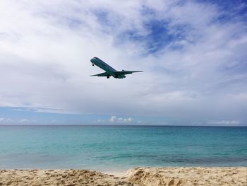 Bird flying over sea against cloudy sky