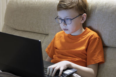 Boy using laptop sitting on sofa at home