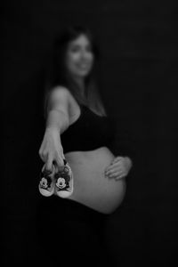 Midsection of woman with arms raised against black background