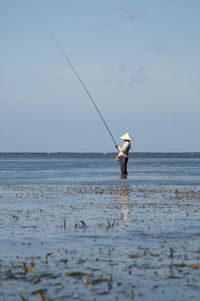 Man fishing in sea against sky