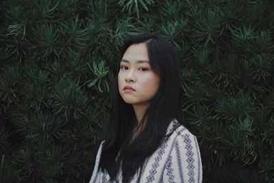 Close-up portrait of young woman standing in grass