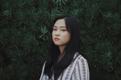 Close-up portrait of young woman standing in grass