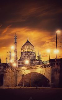 Illuminated building against sky during sunset