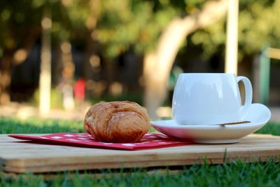 Close-up of croissant and tea cup on cutting board
